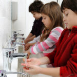 Children washing hands at communal sink